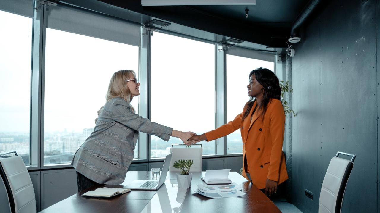 Woman shaking another woman's hand in an office