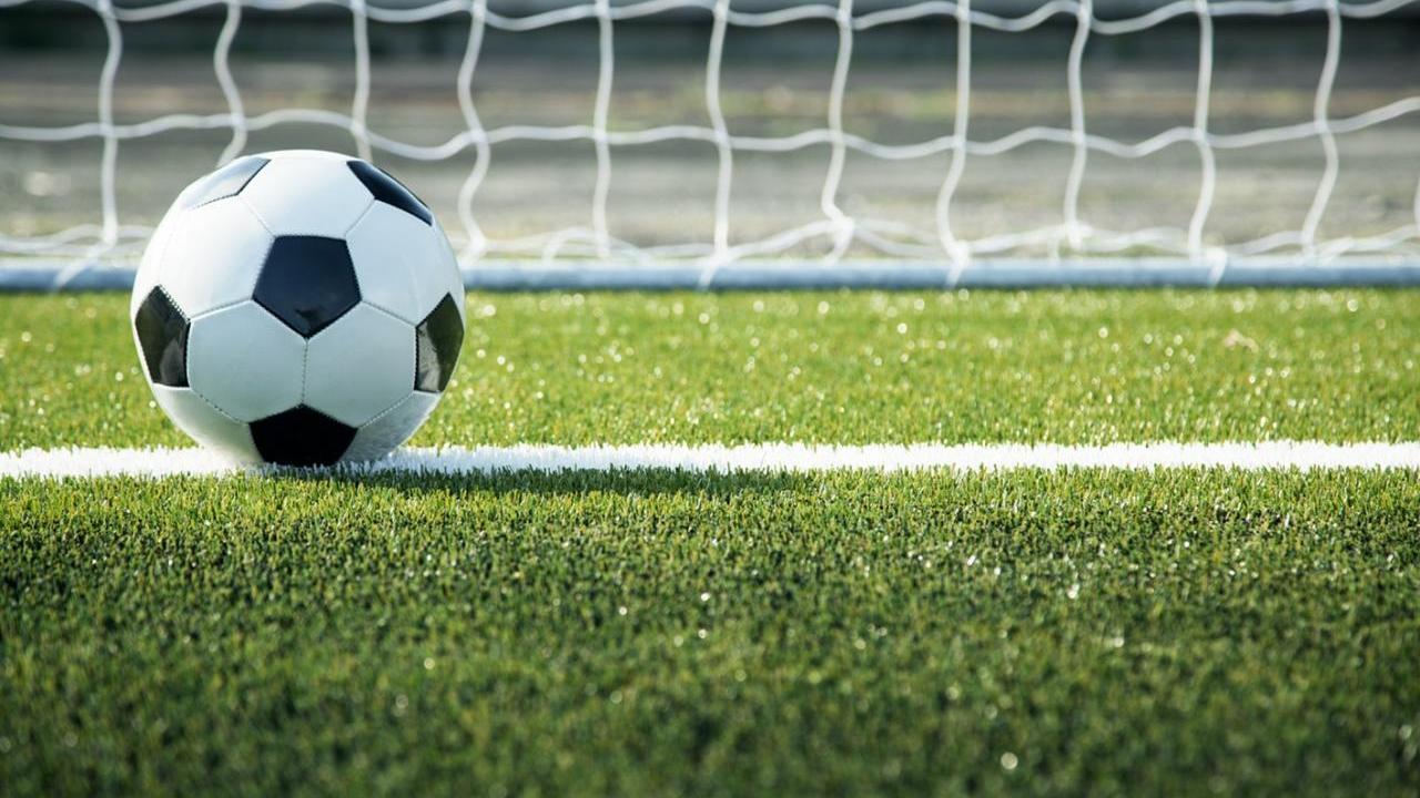 Soccer ball on turf in the foreground with a net in background