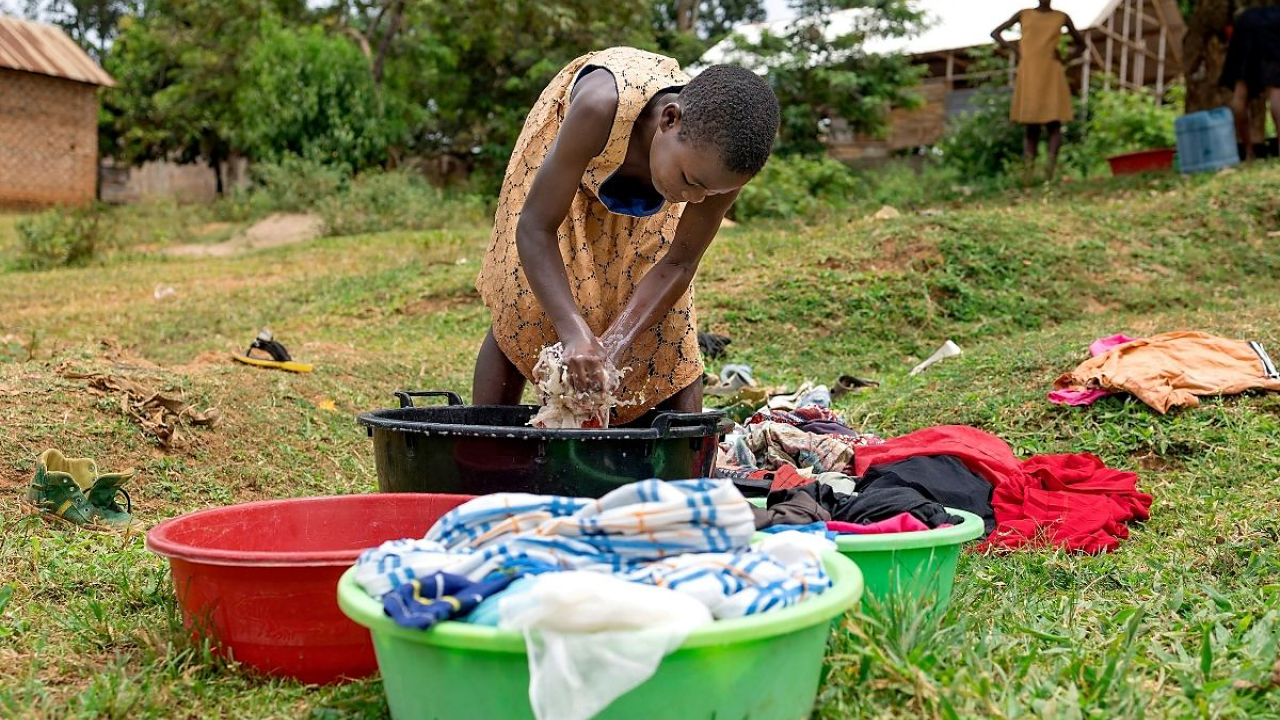 Girl hand washing clothes out of doors
