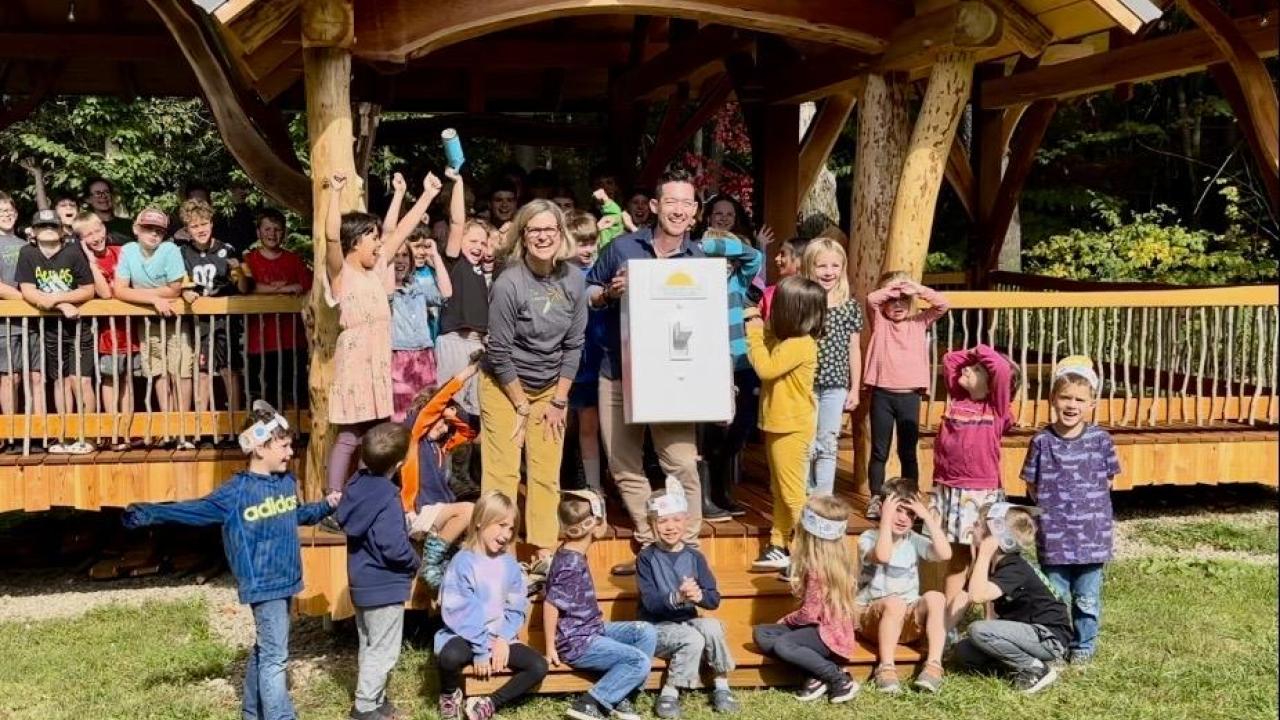 Students cheer as adults flip a life-size light switch at outdoor classroom