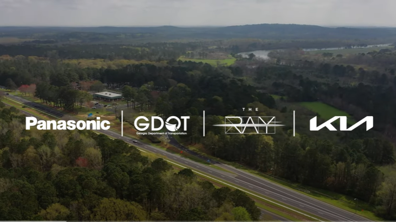 Panasonic logo, GDOT logo, The RAY logo, and Kia Logo overlayed over an aerial view of a highway. 