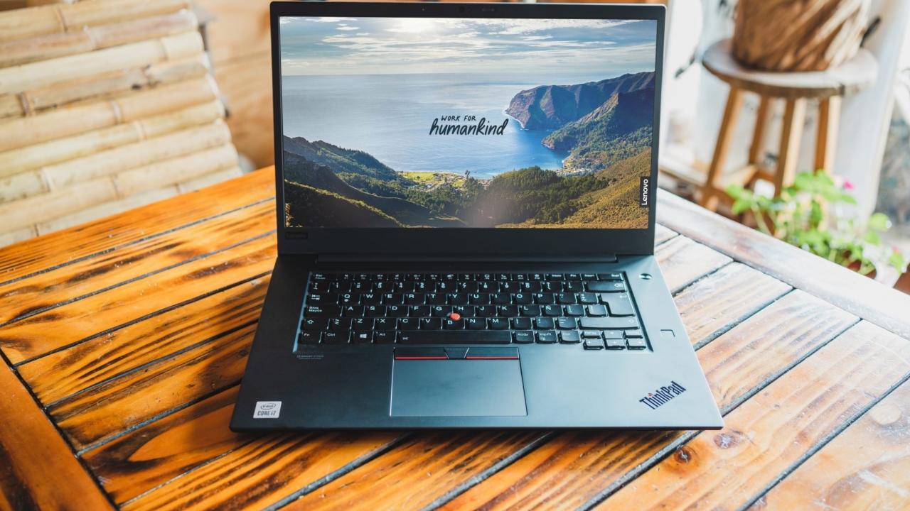 Lenovo ThinkPad on a wood table displaying a Work for Humankind screen saver