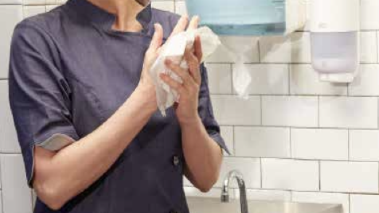 Woman drying her hands using a Tork Reflex dispenser.