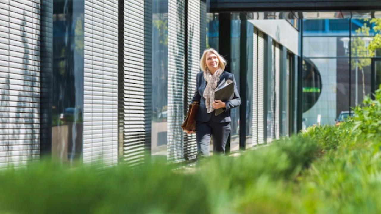 Woman on a college campus walking next to a building.