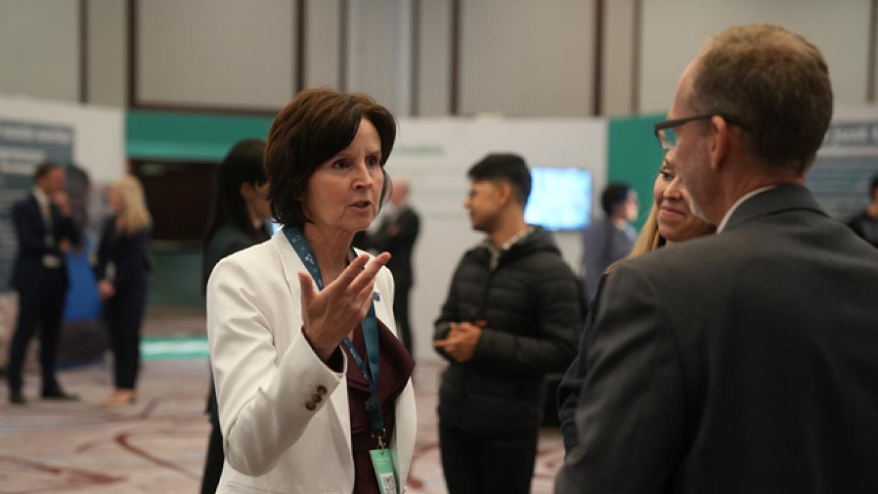 Tracey Campbell talking to another person in a room of others.