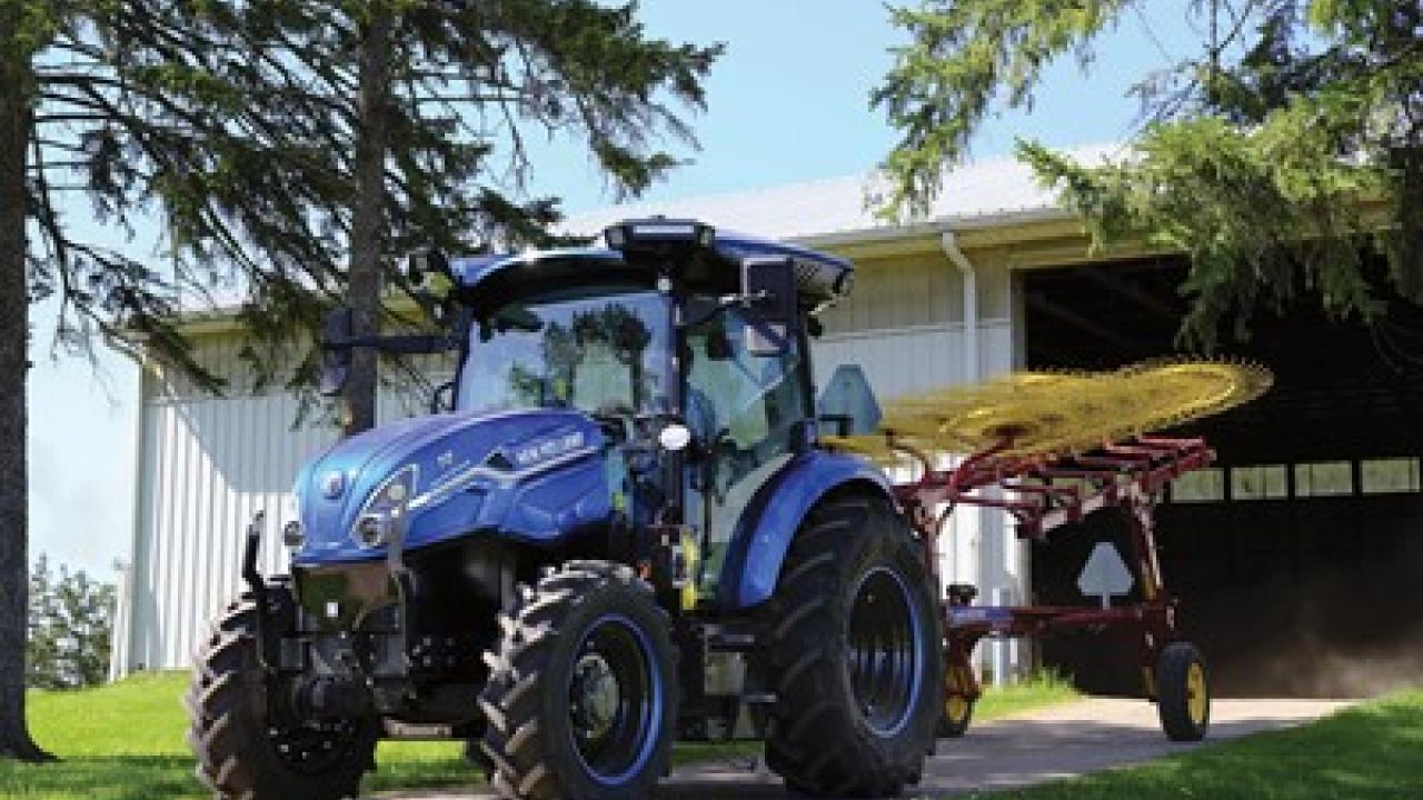 Blue tractor parked on pavement with trees either side