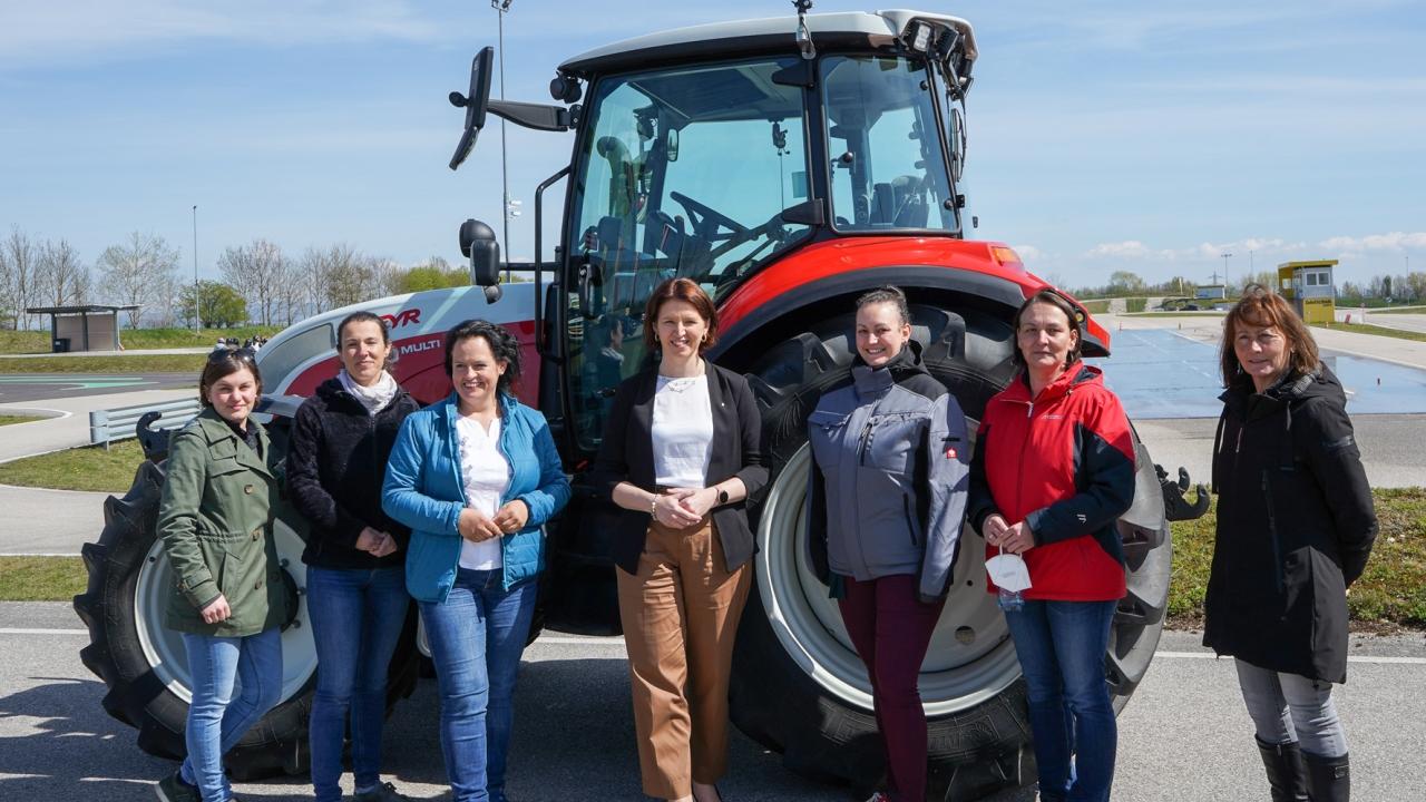 Women students stand in from of a tractor