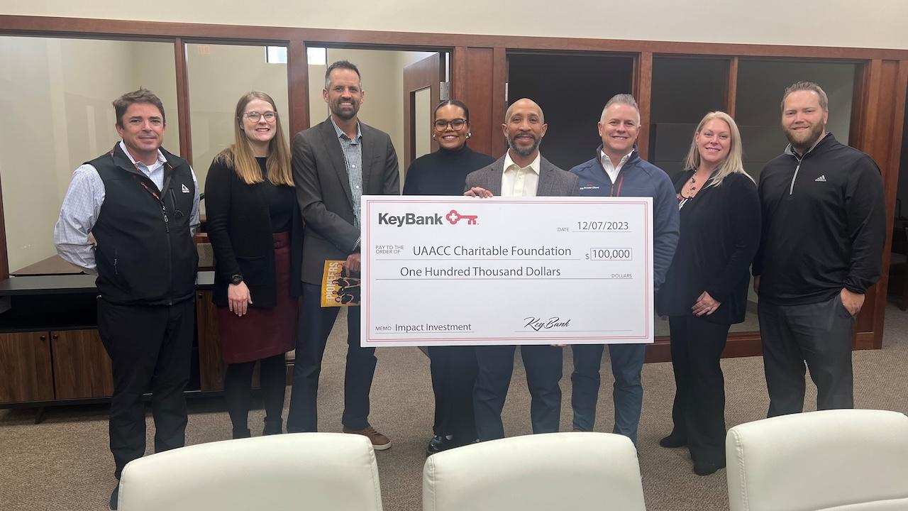 KeyBank and UAACC representatives shown holding a grant check for $100,000.