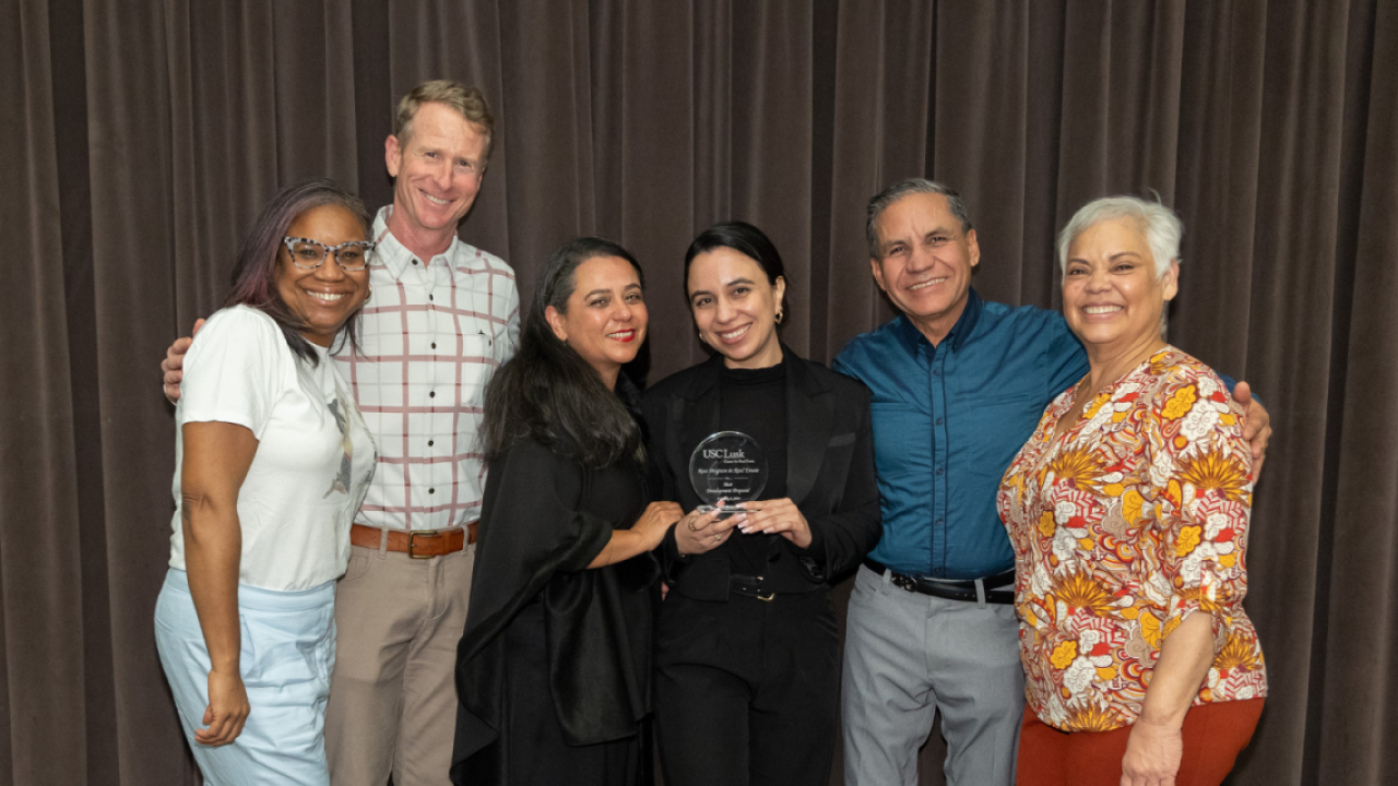 A group of people stood together for a photo holding an award