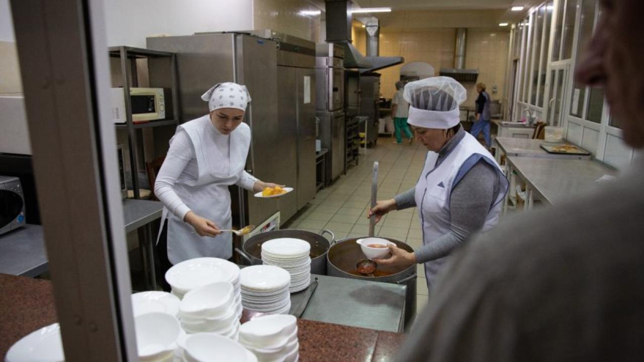 two people serving food from a kitchen