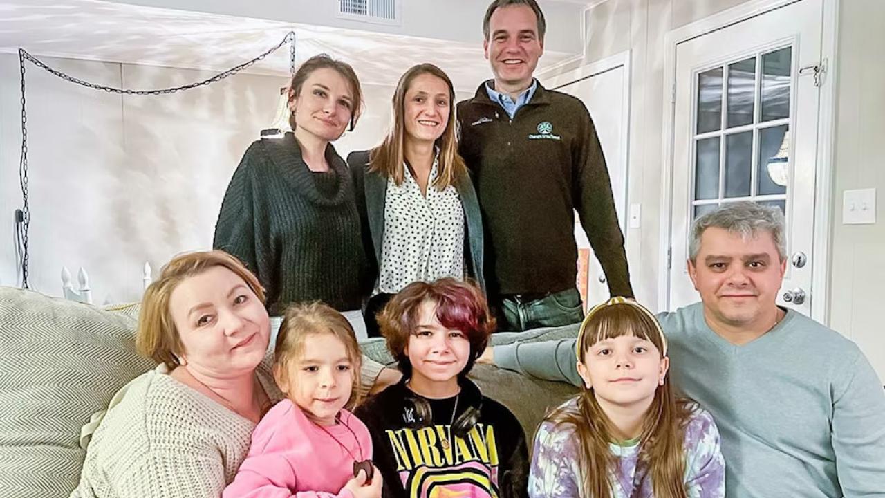 Regions associates stand behind the family sitting on a couch.