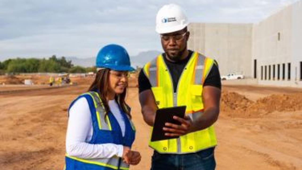 two workers on a construction site using a device 