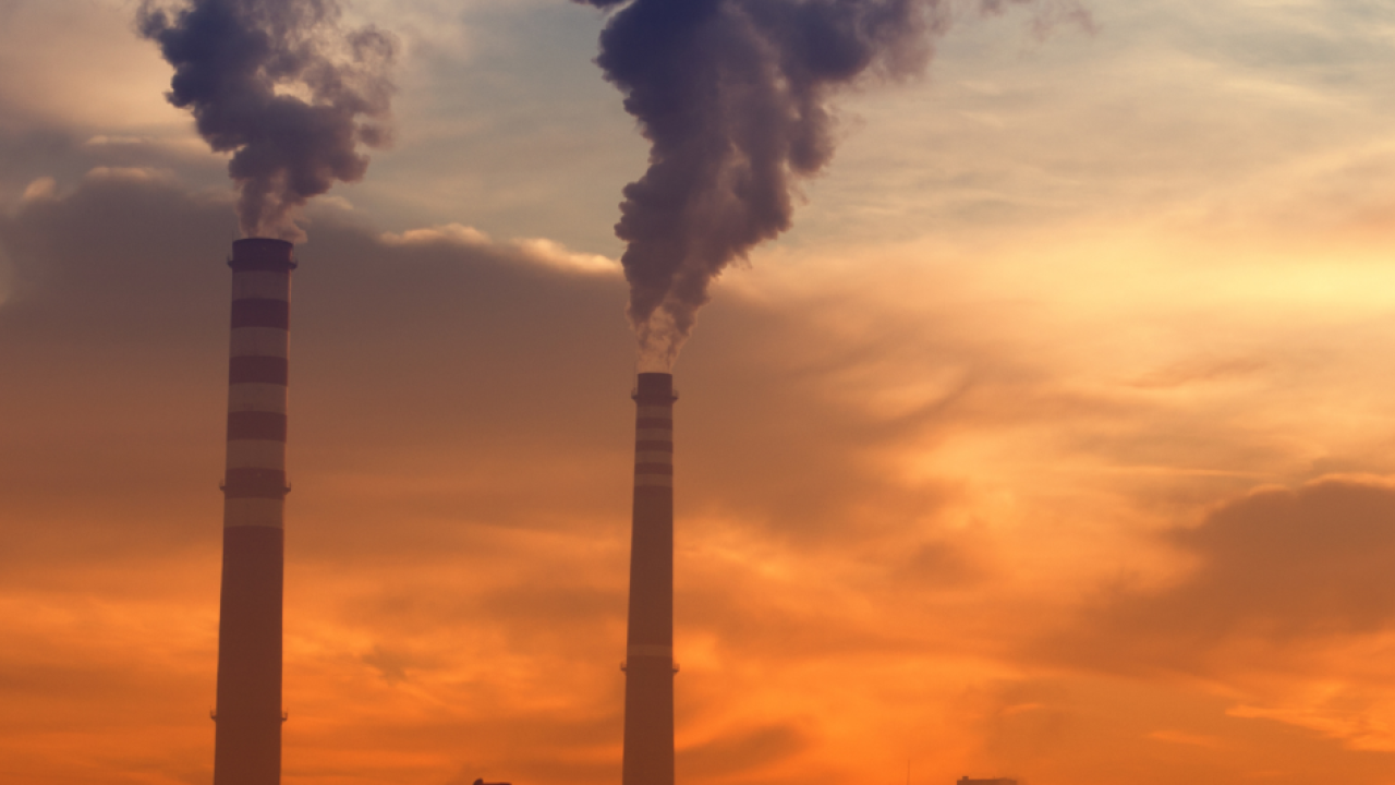 Industrial smoke pumped into a sunset, cloudy sky