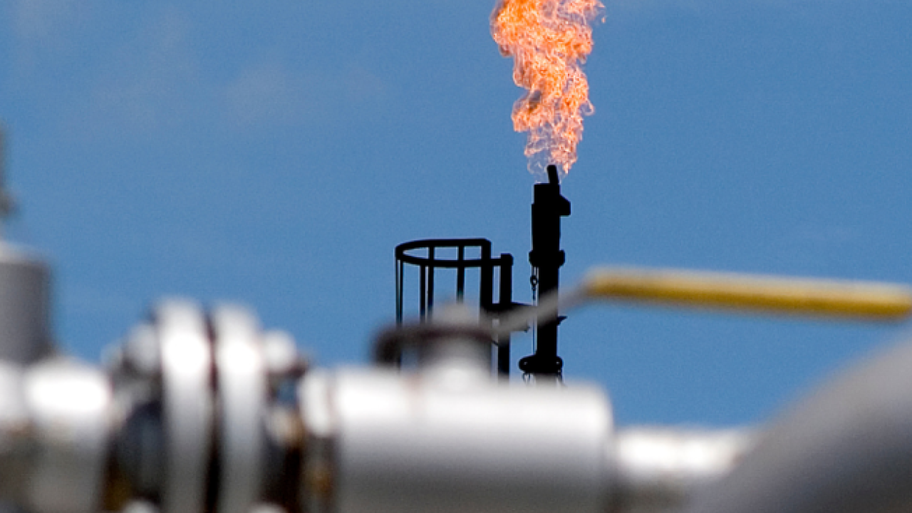 factory or plant emitting a tall flame into a clear, blue sky