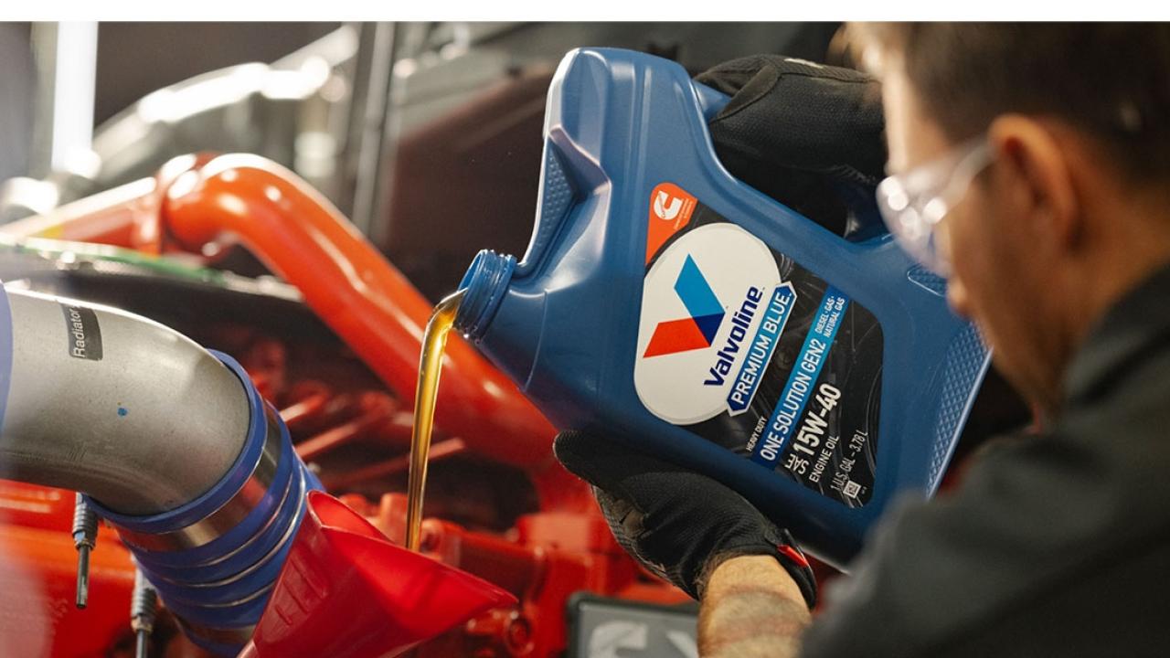 A person pouring a bottle of motor oil 