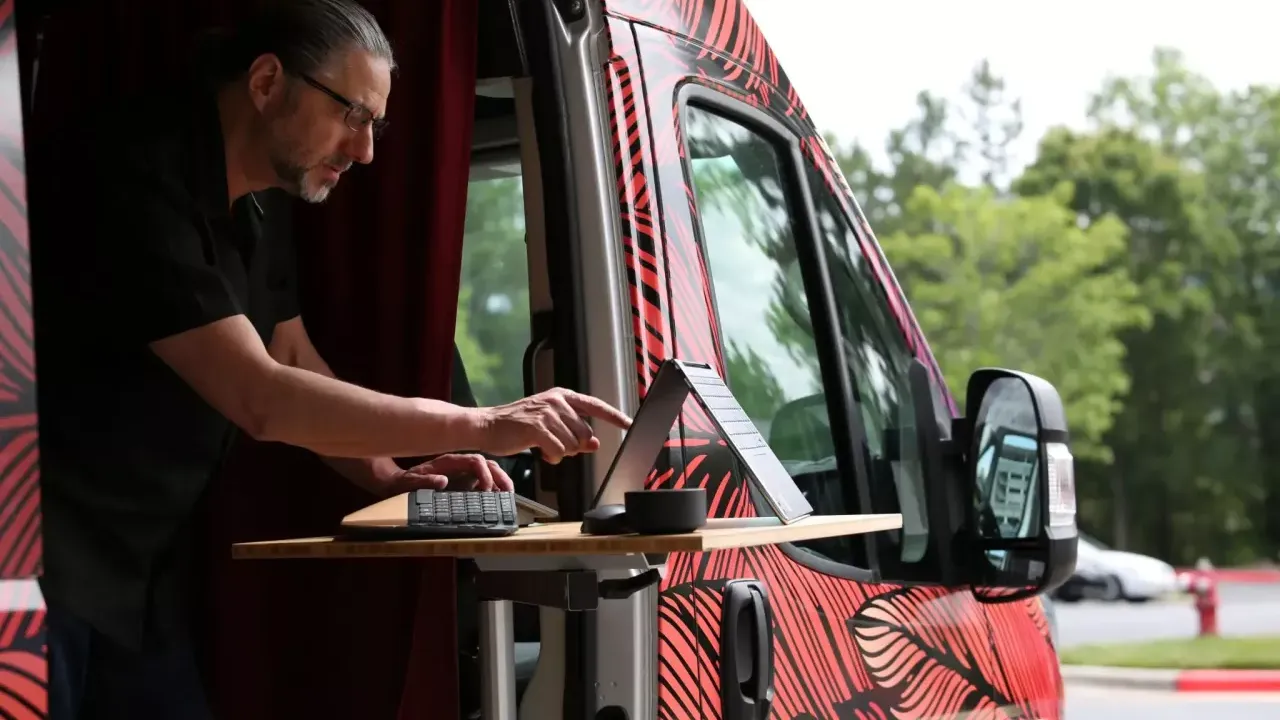 A person working on a laptop out of the side of a van.