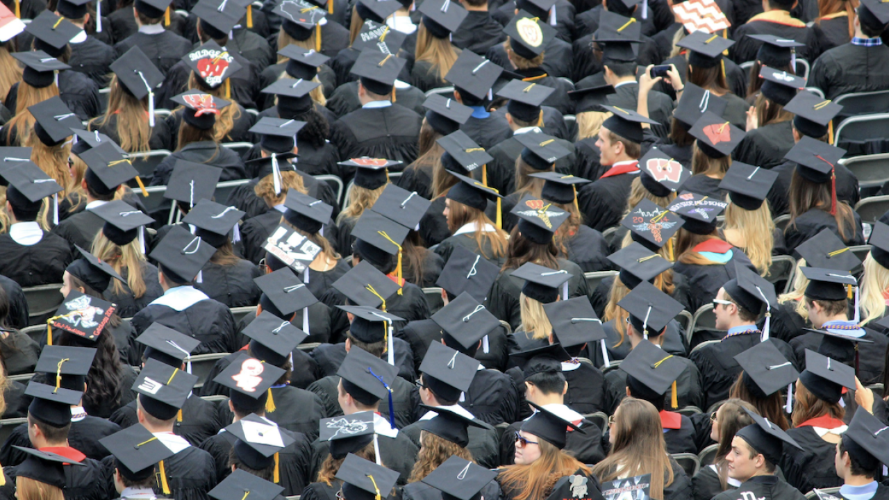 Students shown in cap and gowns at a graduation ceremony.