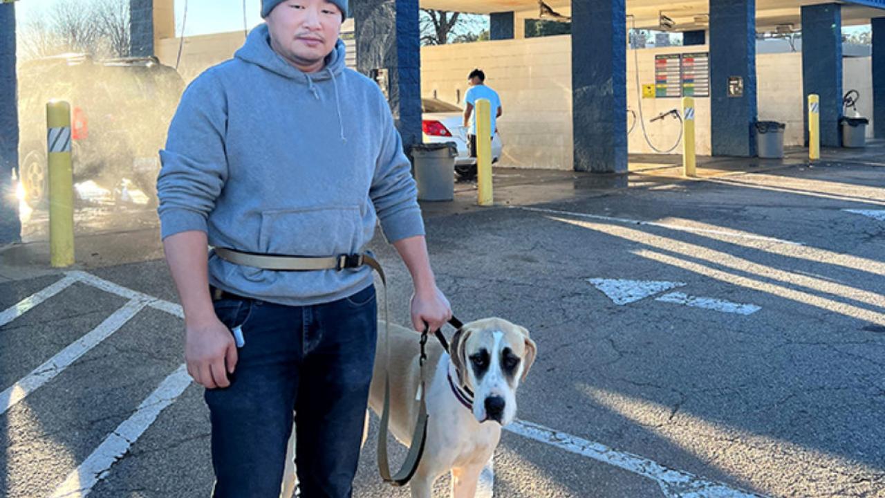 Man stands in front of car wash with his dog