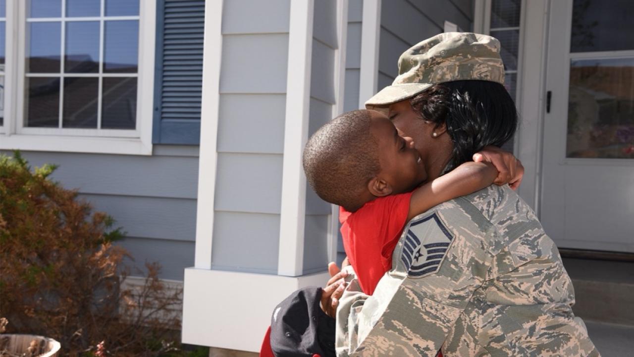 Soldier hugging son in front of house