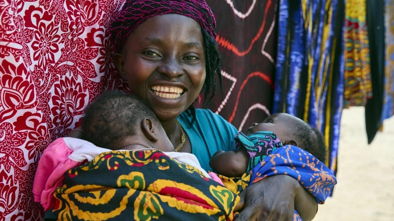 Smiling woman holds her two small children.
