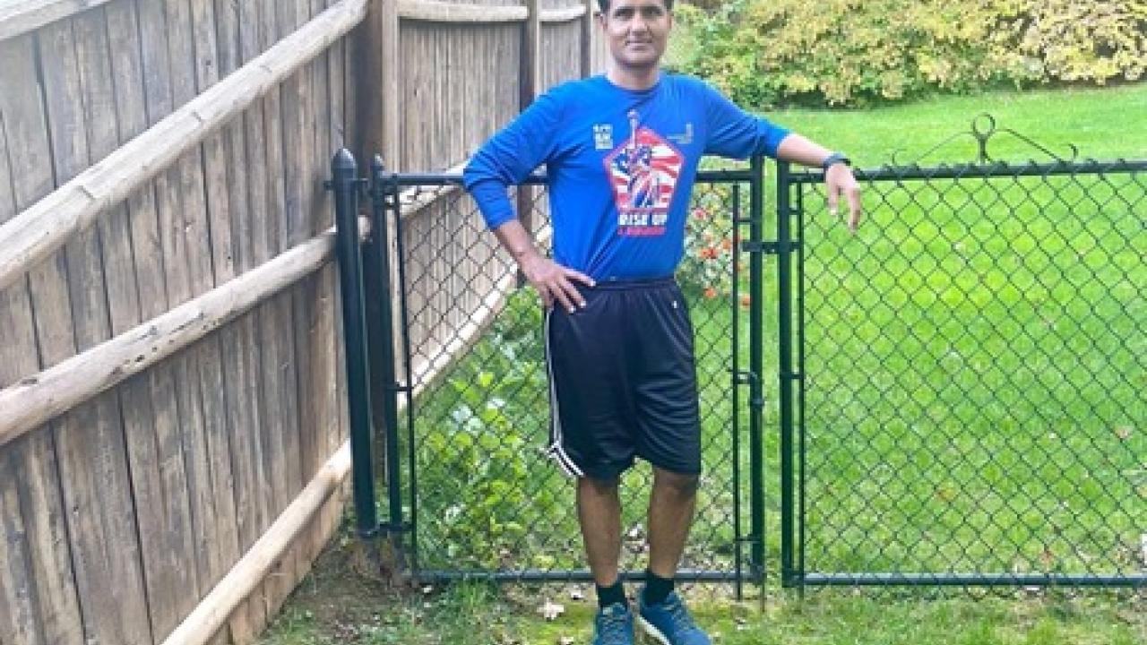 Vinamra Shukla in running gear standing on a green lawn in front of a gate