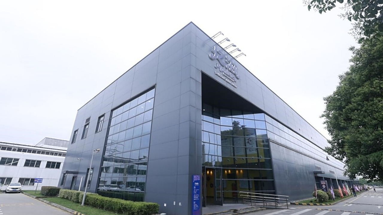 Exterior of an office building. A sign in a foreign language above the high front opening.