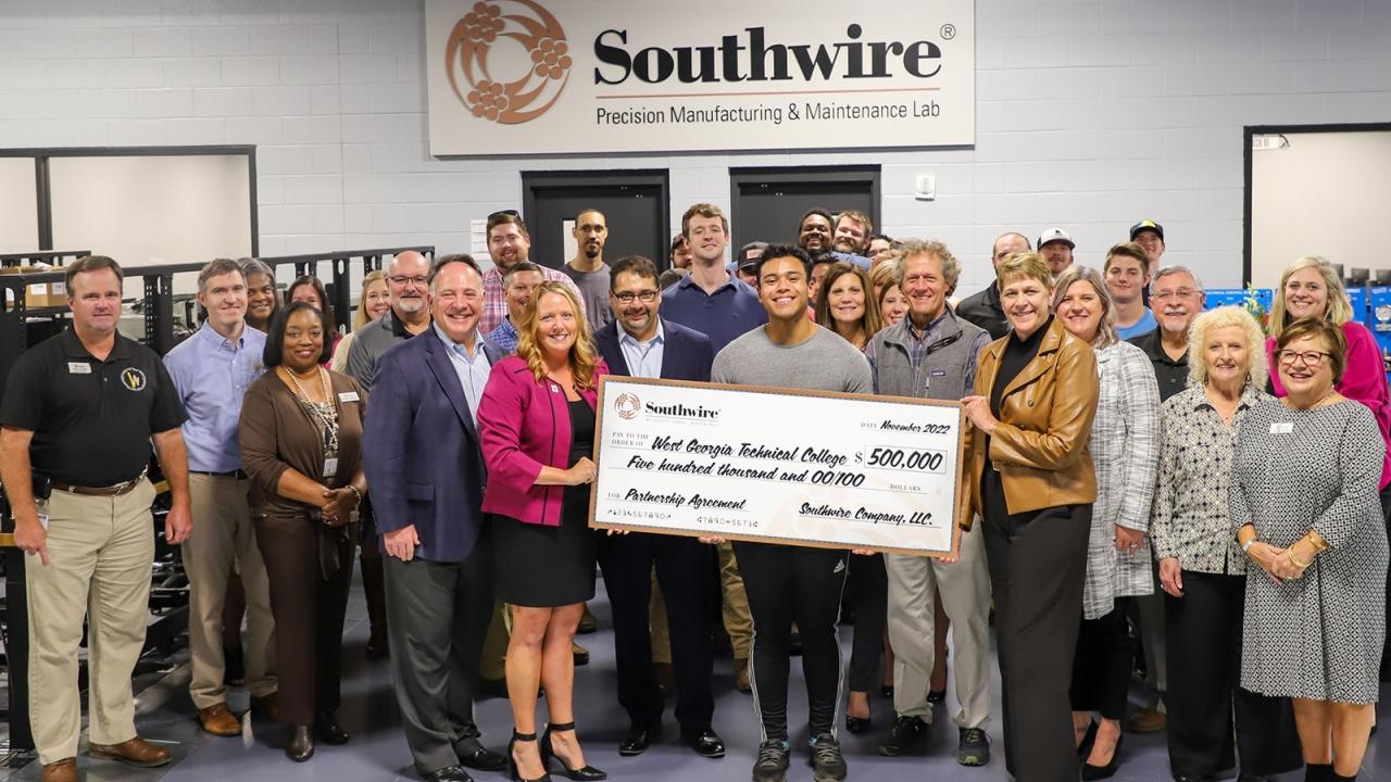 A group of people standing, those central are holding a large check to WGTC from Southwire.