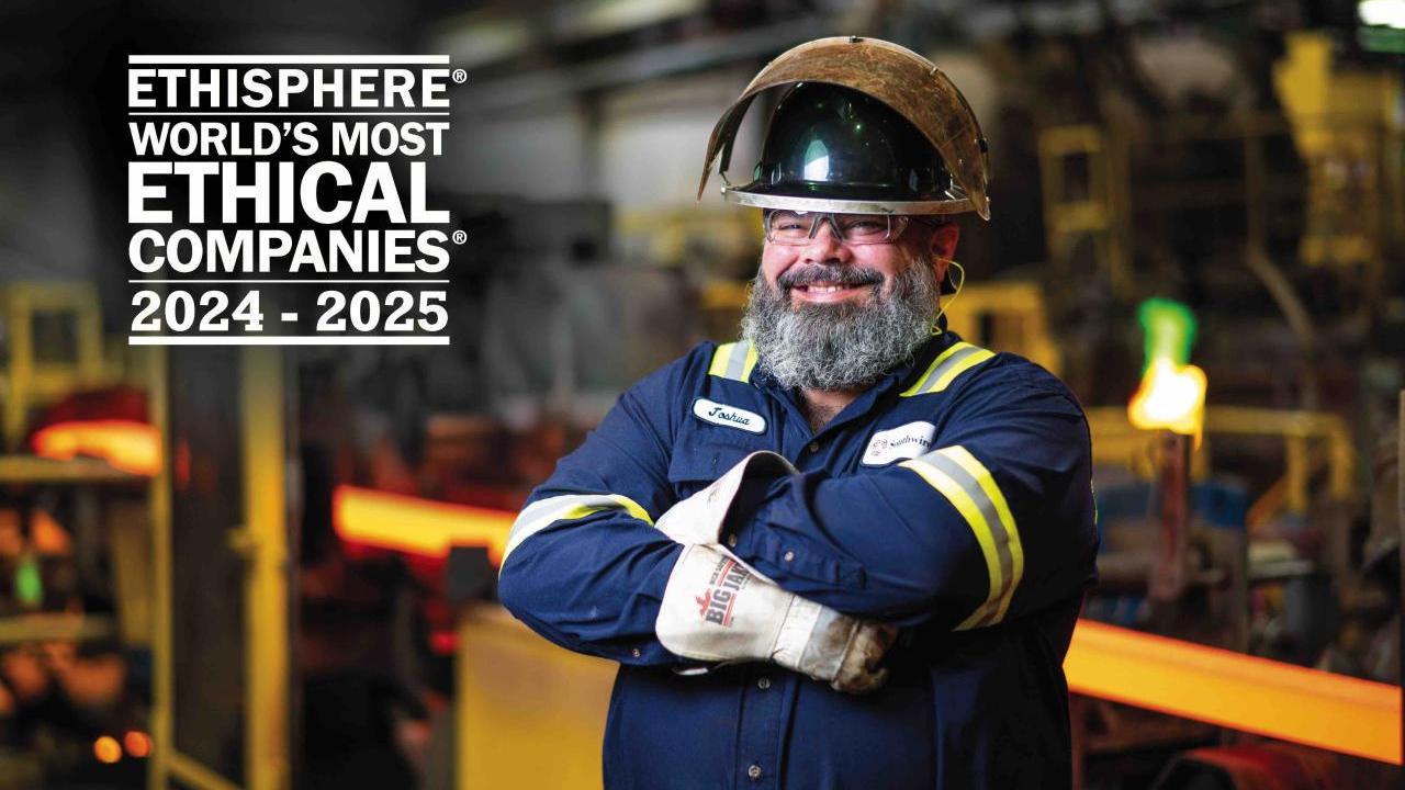 Factory worker smiling with arms crossed.