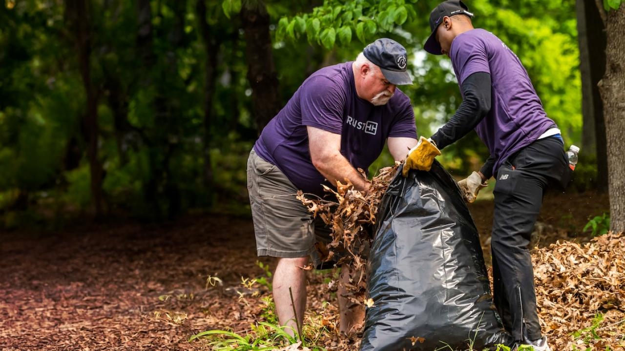 Two Truist volunteers stuffing debris into a bag.