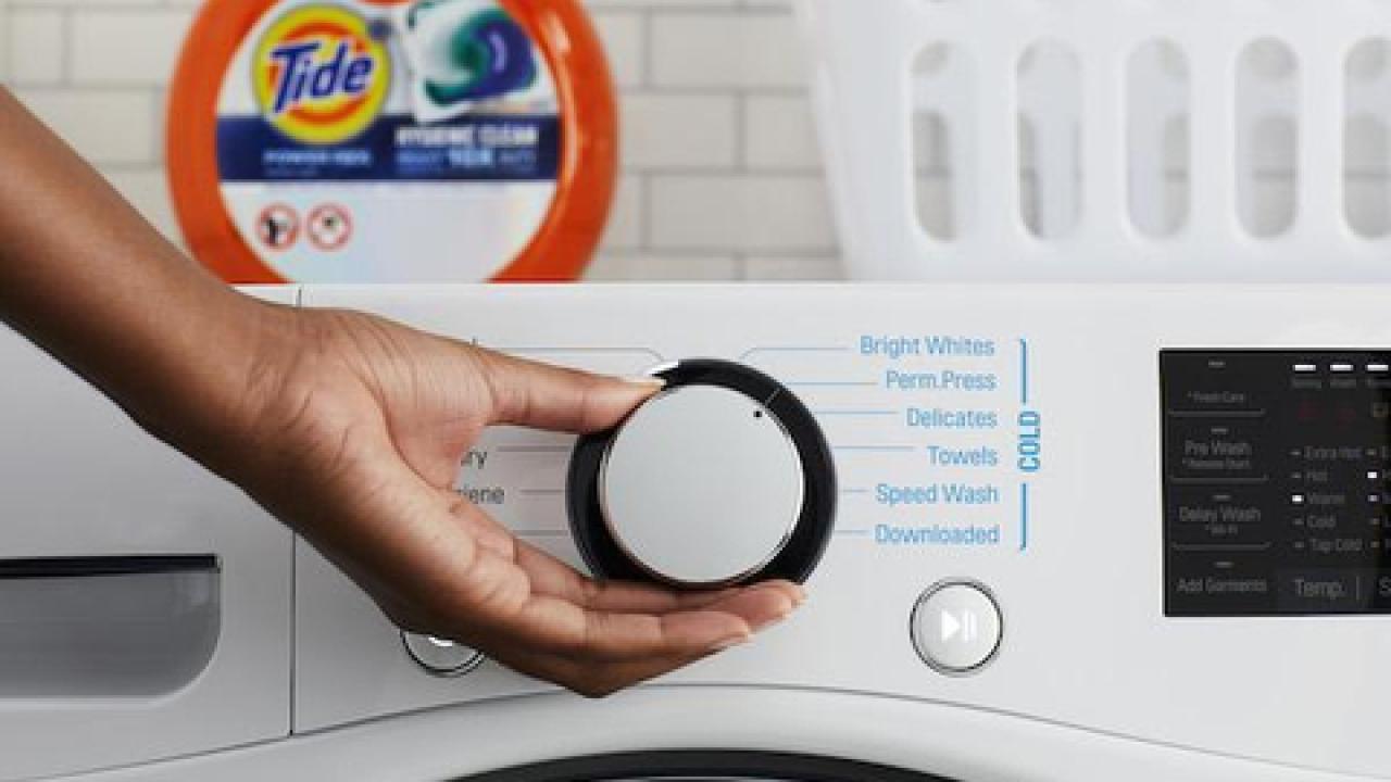 Person turning the dial on a washing machine 