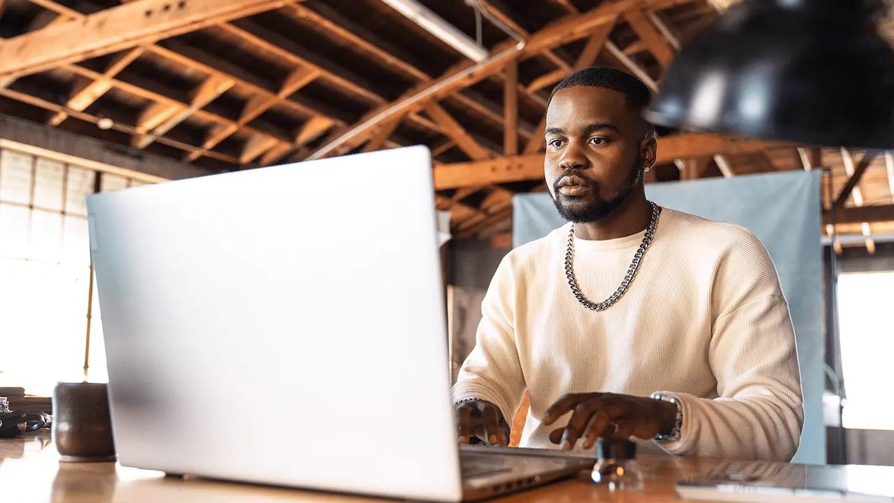 Male sitting in front of a laptop at a desk.