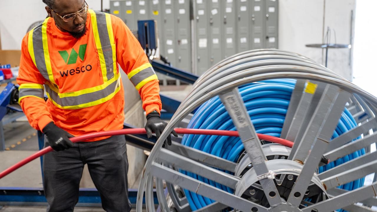 Wesco employee in safety gear reeling in a cable.