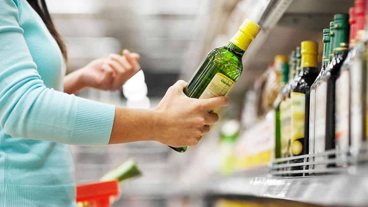 Woman choosing olive oil off shelf