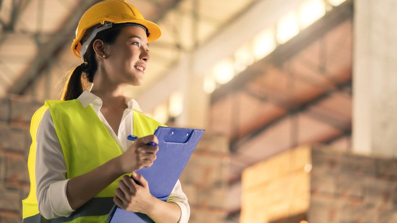 Woman wearing hard hat and holding clipboard