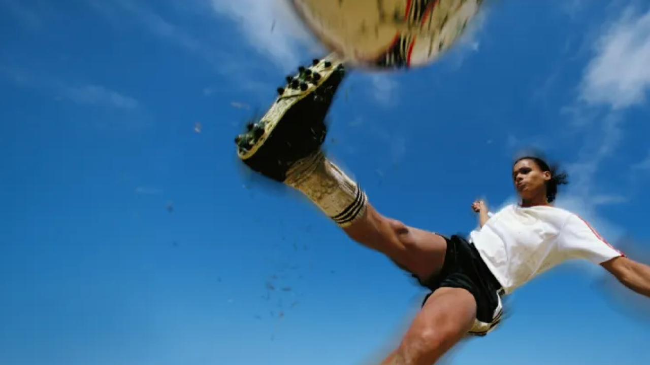 Female soccer player kicking a ball.