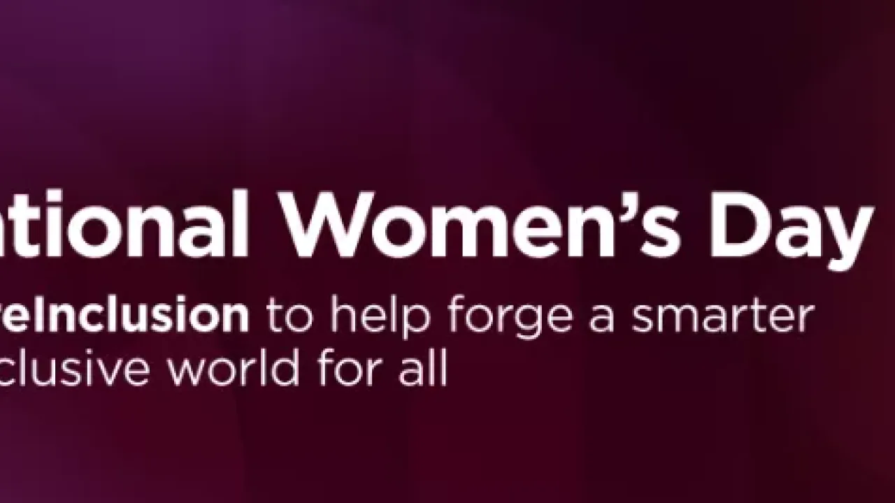 International Women's Day banner and Lenovo logo. A person stepping up large red blocks outdoors.