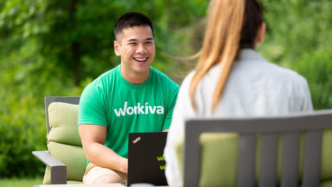 Workiva team members shown working on a back porch with a laptop.