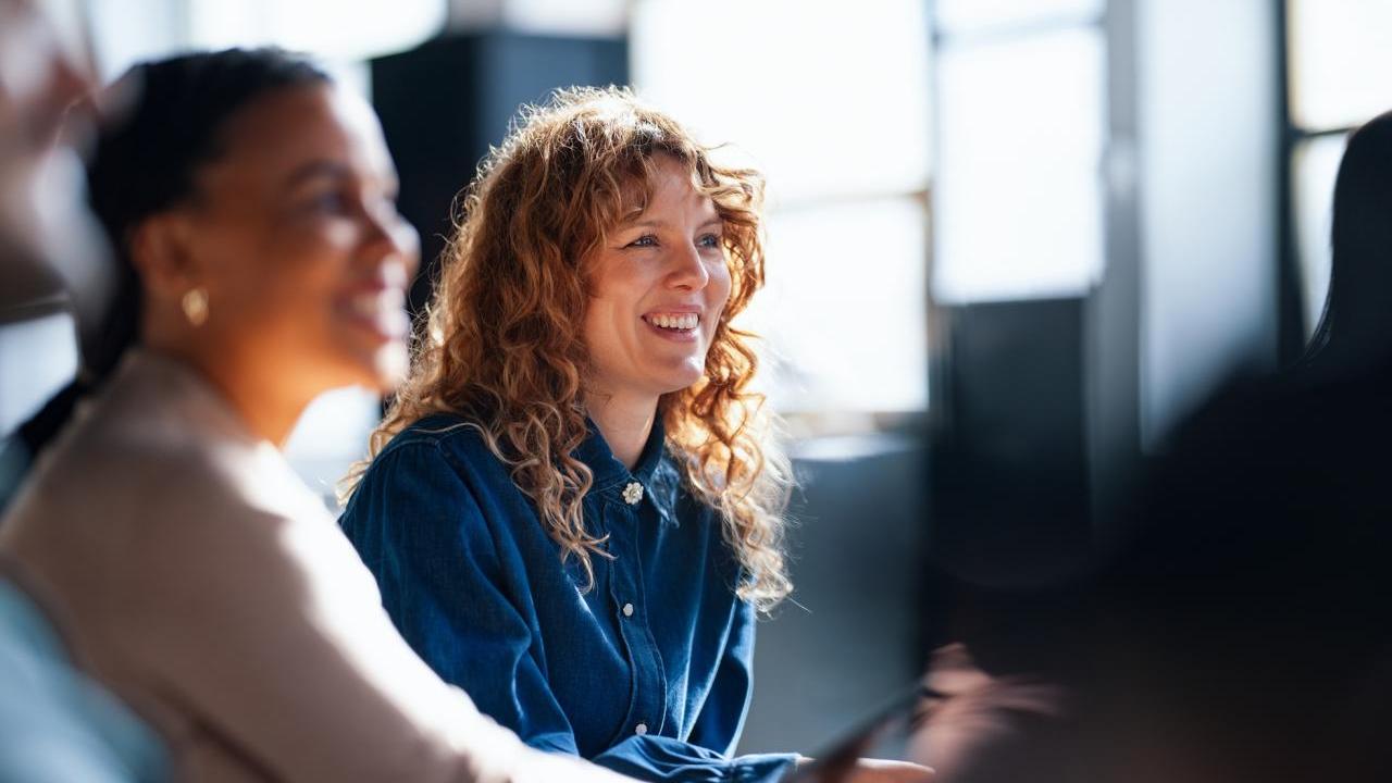 Smiling Colleagues Engaging During an Informal Office Meeting in Brightly Lit Space