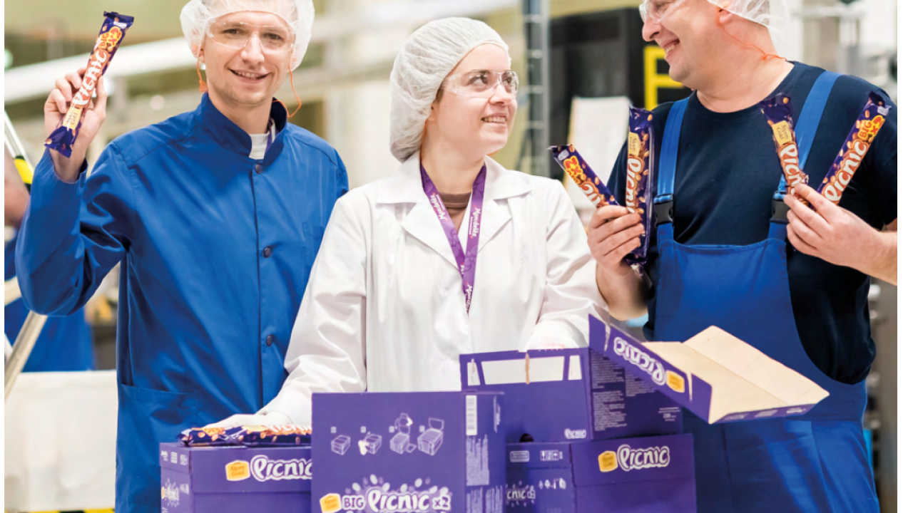 Three workers in their uniforms holding Mondelēz products