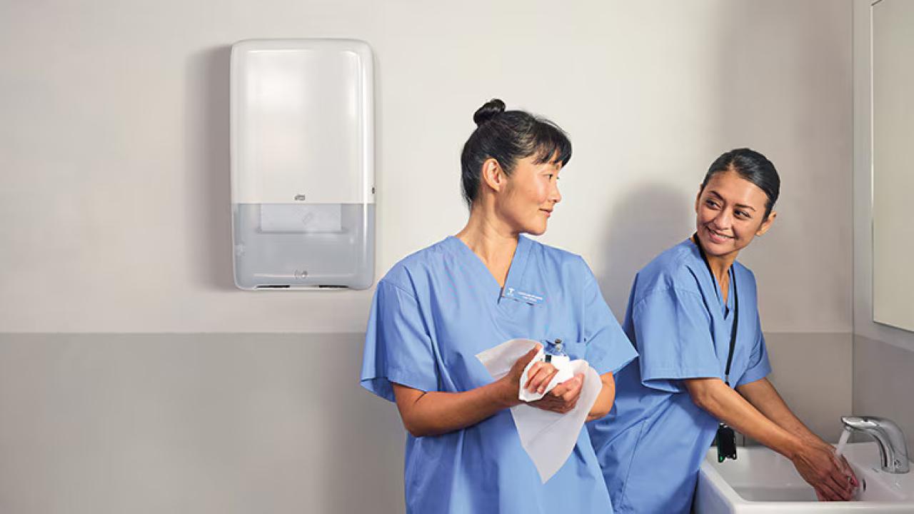 Two healthcare workers washing and drying their hands.