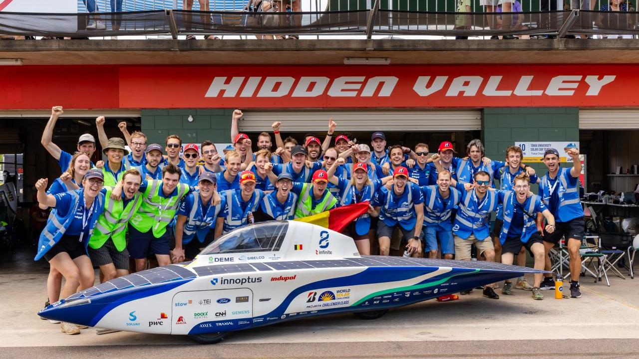 Team Innoptus stood behind a solar car 