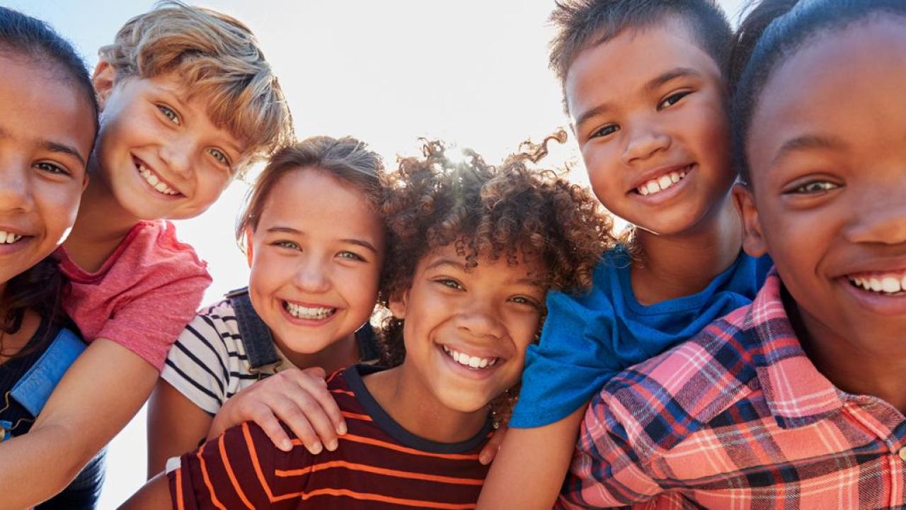 A group of children leaning on each other, smiling  