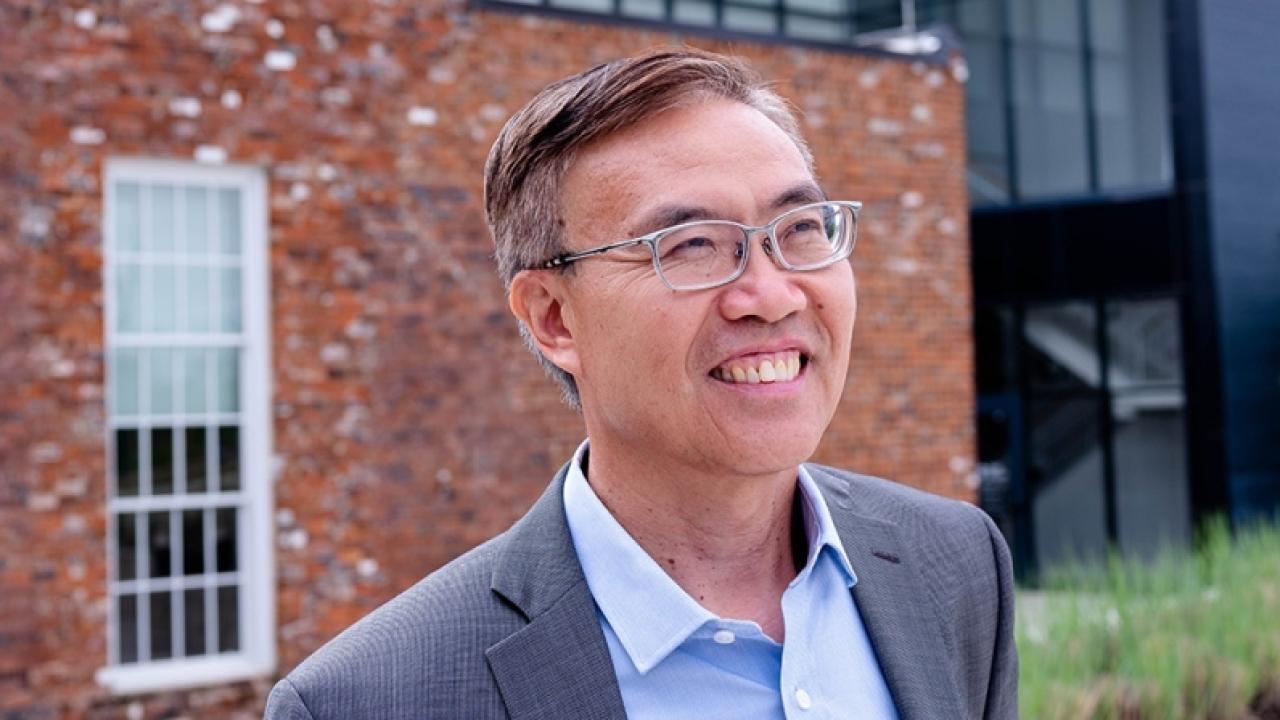 Ben Zhang outside, a brick building in the background