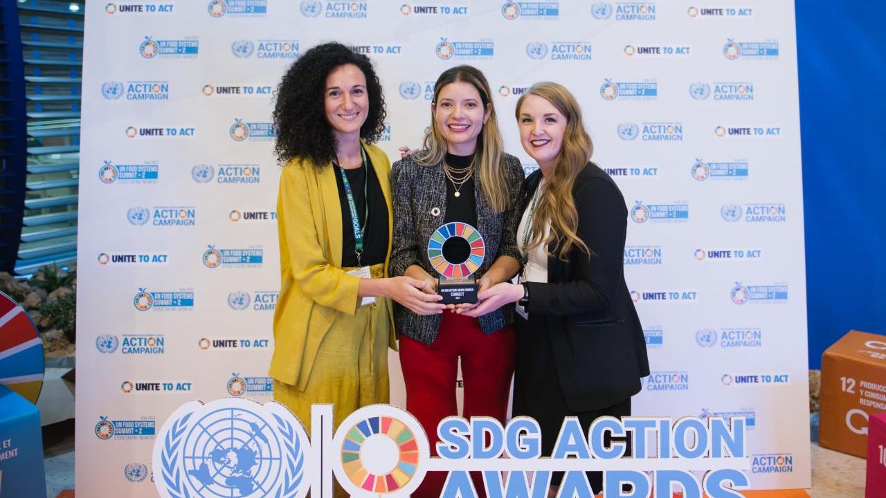 Three smiling people holding an award.