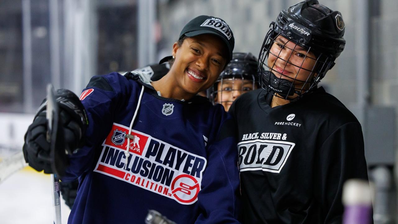 Blake Bolden in a Player Inclusion Coalition jersey poses with a participant in Black, Silver & Bold gear during a hockey clinic.