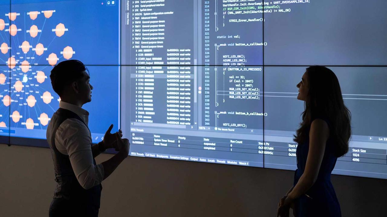 people looking at a computer screen of code