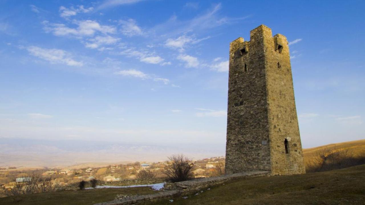 Stone tower shown on top of a hill.