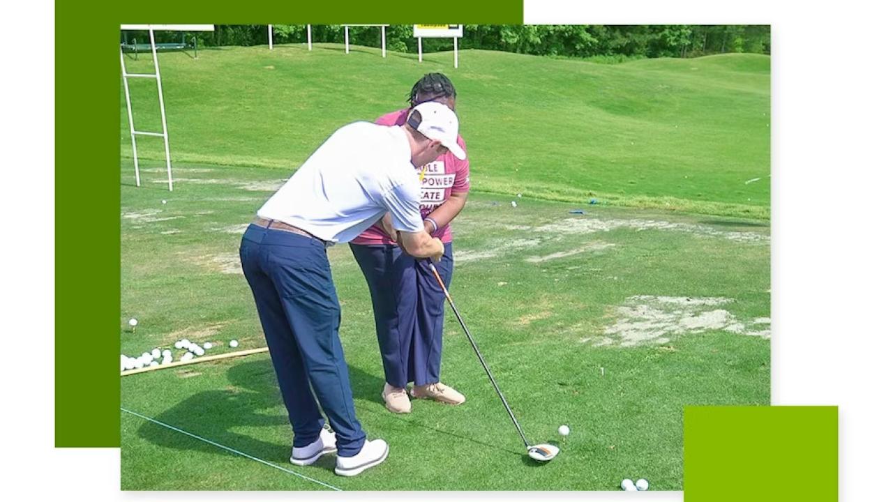 An instructor helping another with a golf club.
