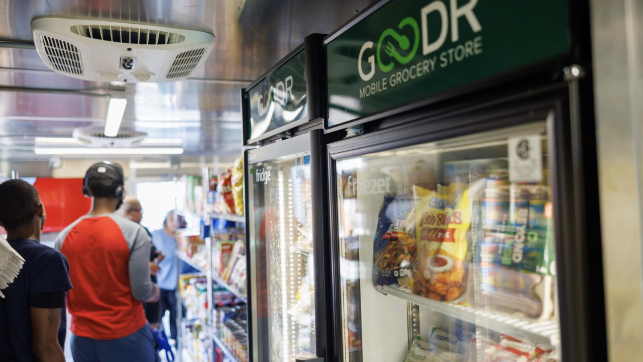 People in a line past a Goodr labeled fridge in a mobile grocery store