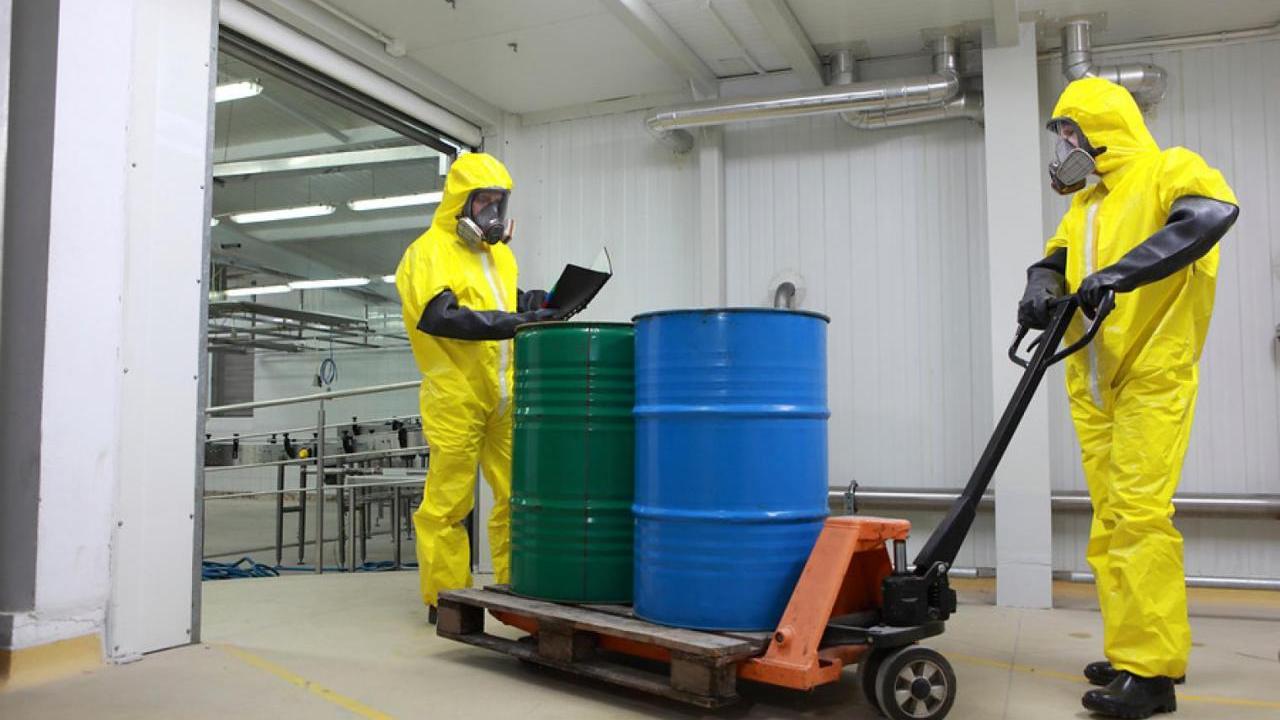 Workers in PPE transport chemicals in a warehouse